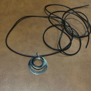 silver-tone pendant necklace with two interlocking circles on a black cord